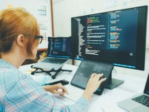 a lady working in front of her PC and tablet on code snippets