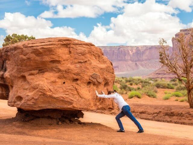 a person pushing a huge bolders to o avail