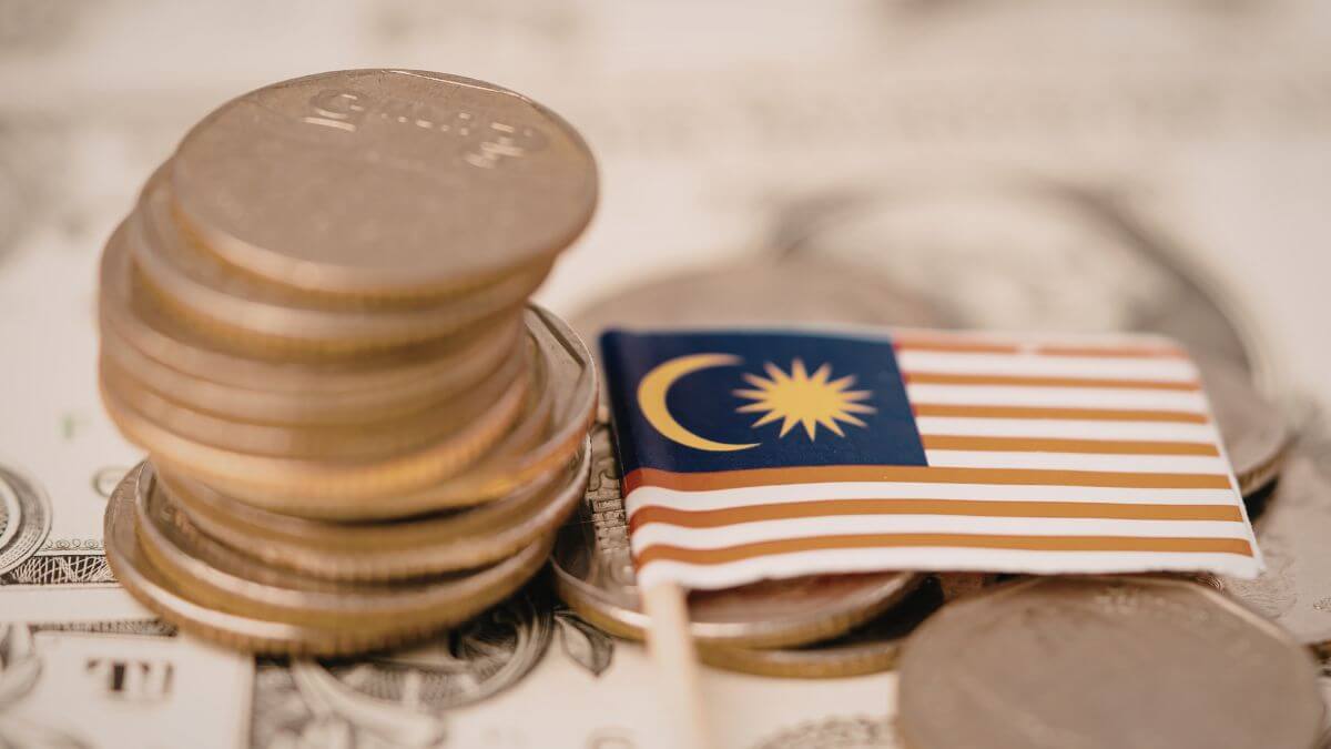 Malaysian flag and stack of coins on currency background