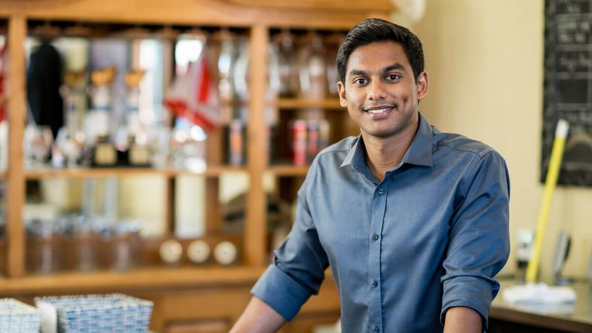 a happy cafe owner standing behind the bar